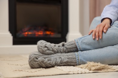 Photo of Woman resting near fireplace at home, closeup