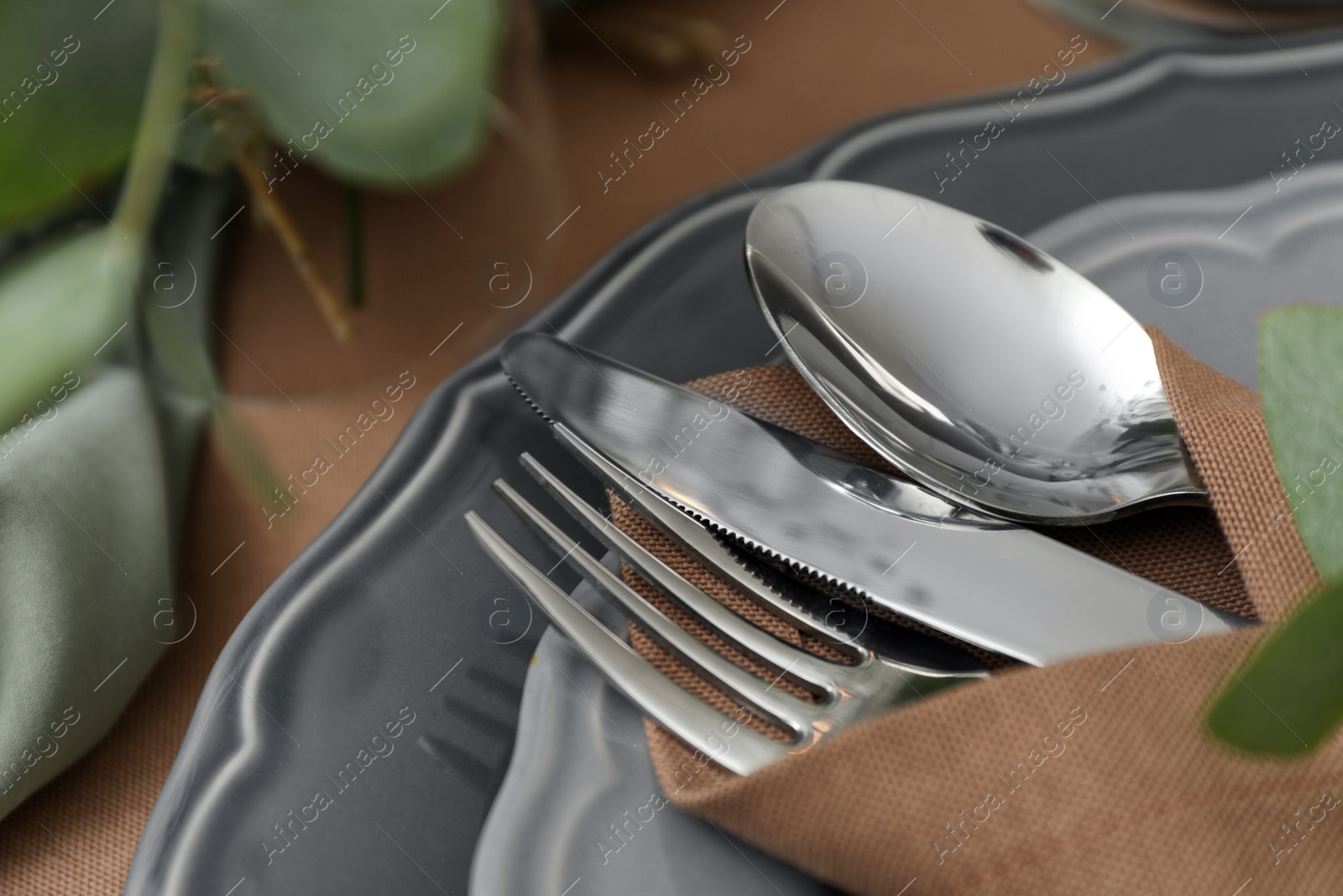 Photo of Napkin with cutlery on plate, closeup. Festive table setting