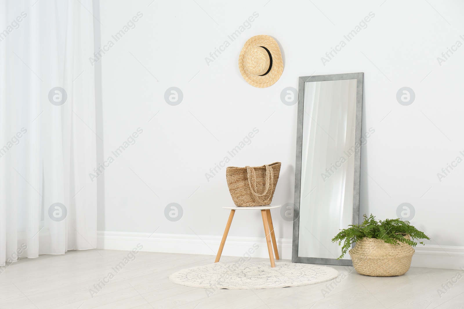 Photo of Modern interior with large mirror and fern plant near white wall