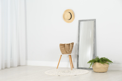 Modern interior with large mirror and fern plant near white wall
