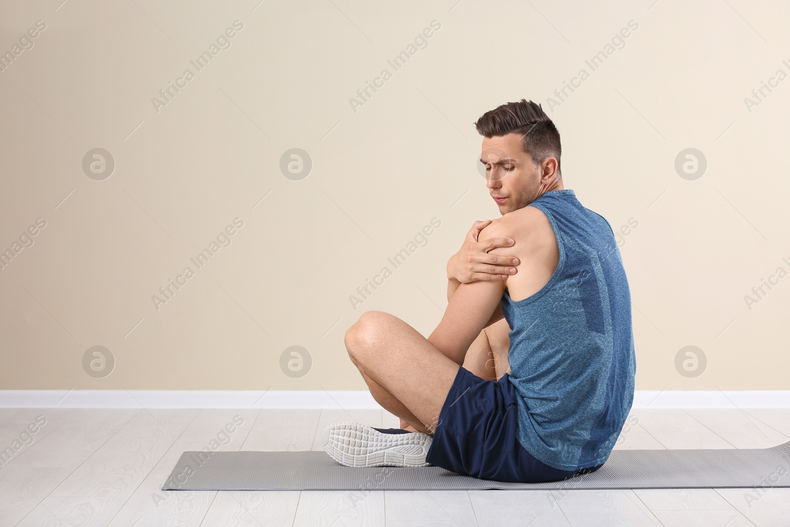 Photo of Male athlete suffering from shoulder pain during training indoors