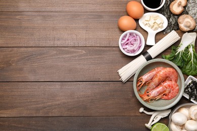 Cooking delicious ramen soup. Different ingredients on wooden table, flat lay. Space for text