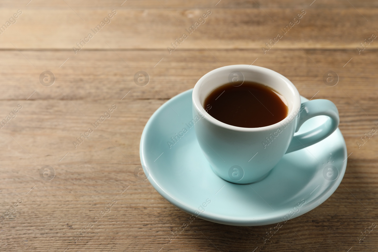 Photo of Tasty coffee in cup on wooden table, closeup. Space for text