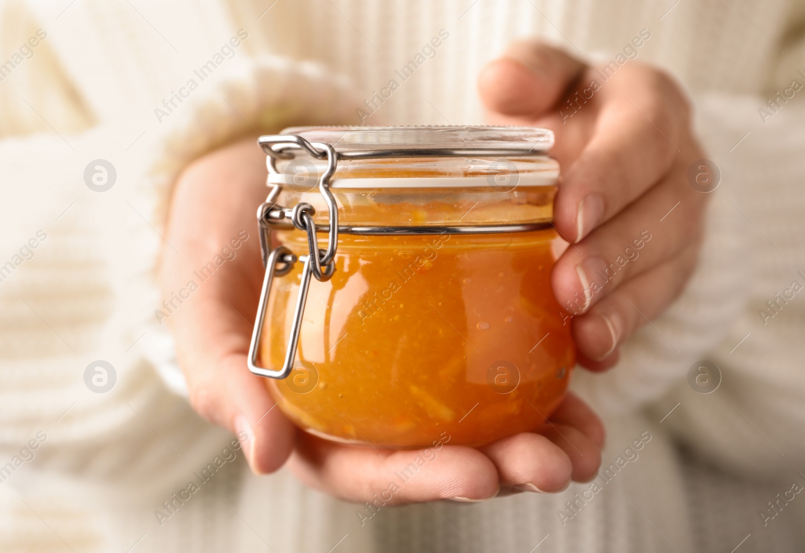 Photo of Woman with jar of orange jam, closeup