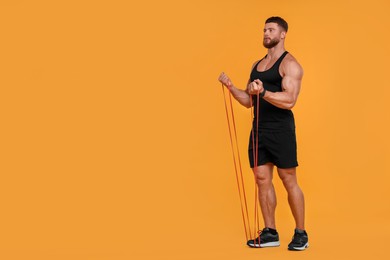 Photo of Young man exercising with elastic resistance band on orange background. Space for text