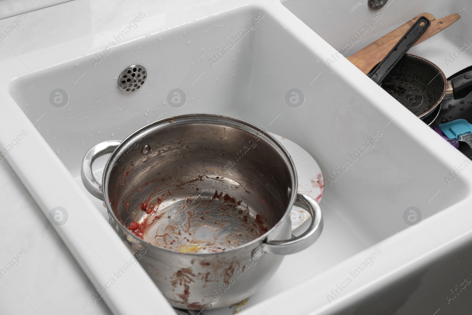Photo of Sink with dirty metal pot in kitchen