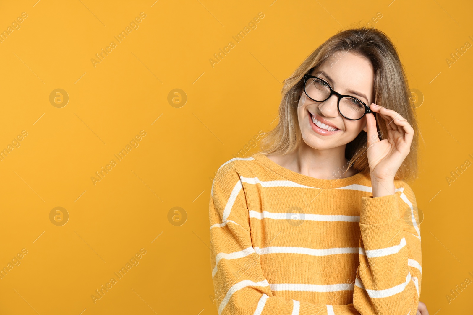 Photo of Portrait of happy young woman with beautiful blonde hair and charming smile on yellow background. Space for text