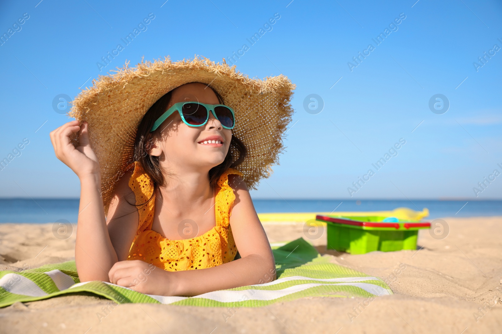 Photo of Cute little child lying at sandy beach on sunny day