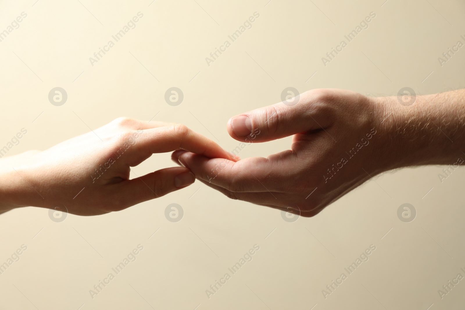 Photo of Man and woman holding hands together on beige background, closeup