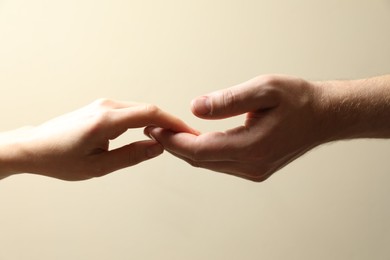 Man and woman holding hands together on beige background, closeup