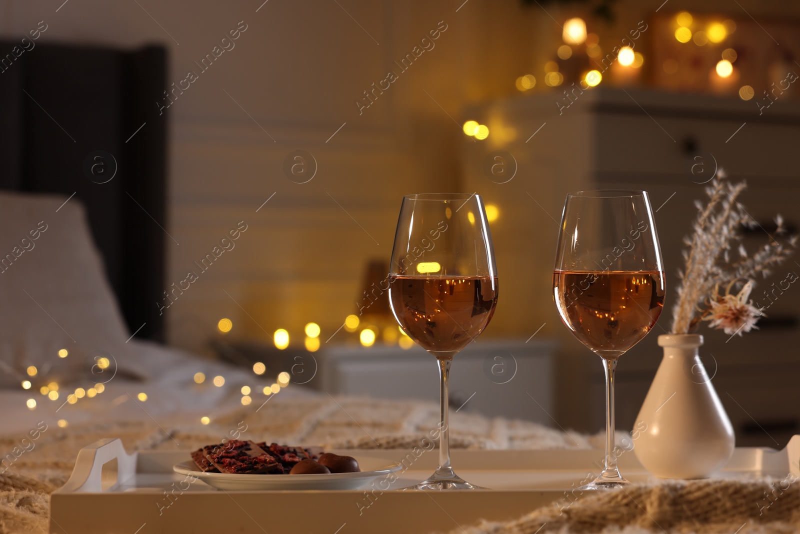 Photo of Tray with glasses of wine on bed, space for text. Romantic evening