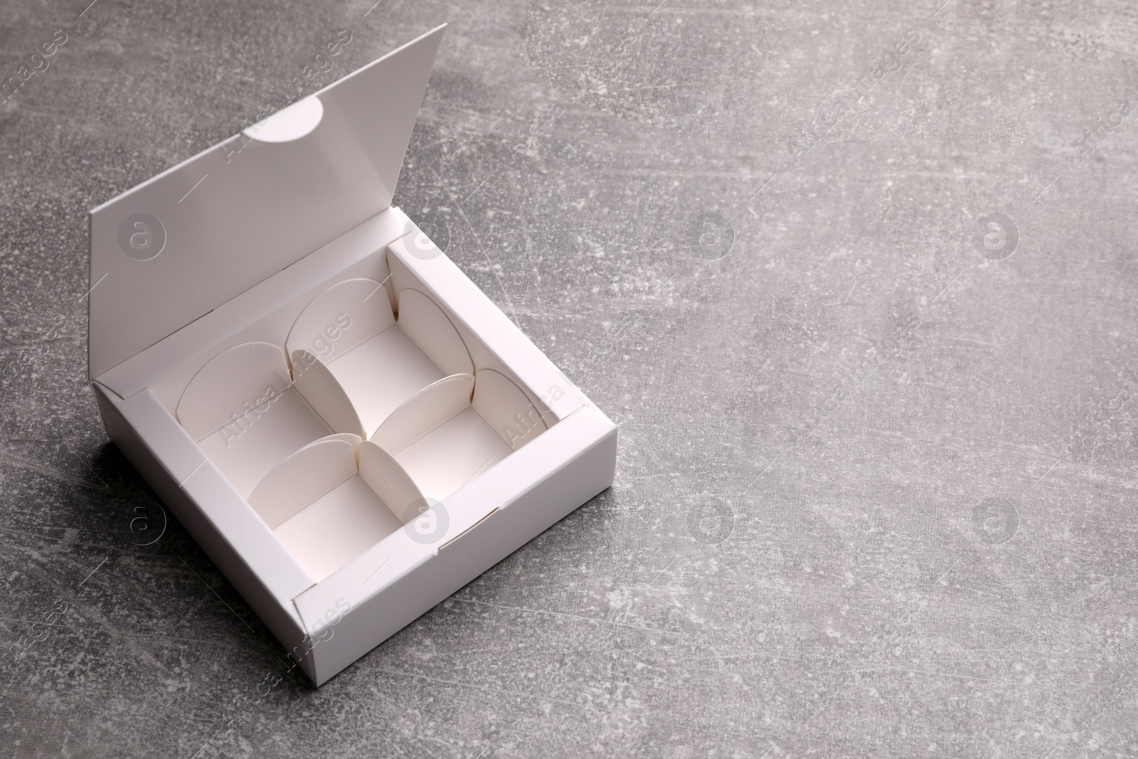 Photo of Empty white candy box on light grey table, space for text