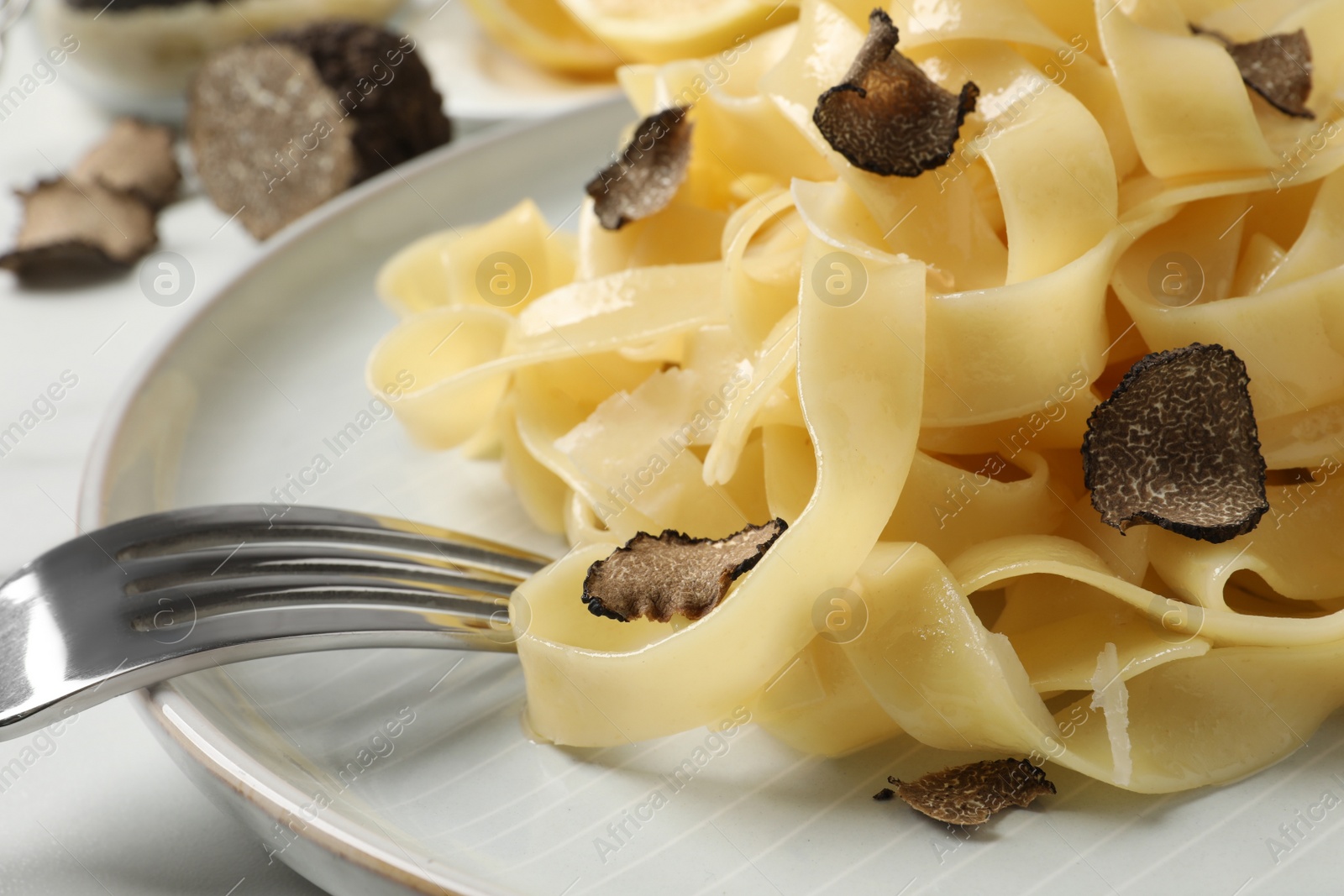 Photo of Delicious pasta with truffle slices served on white table, closeup