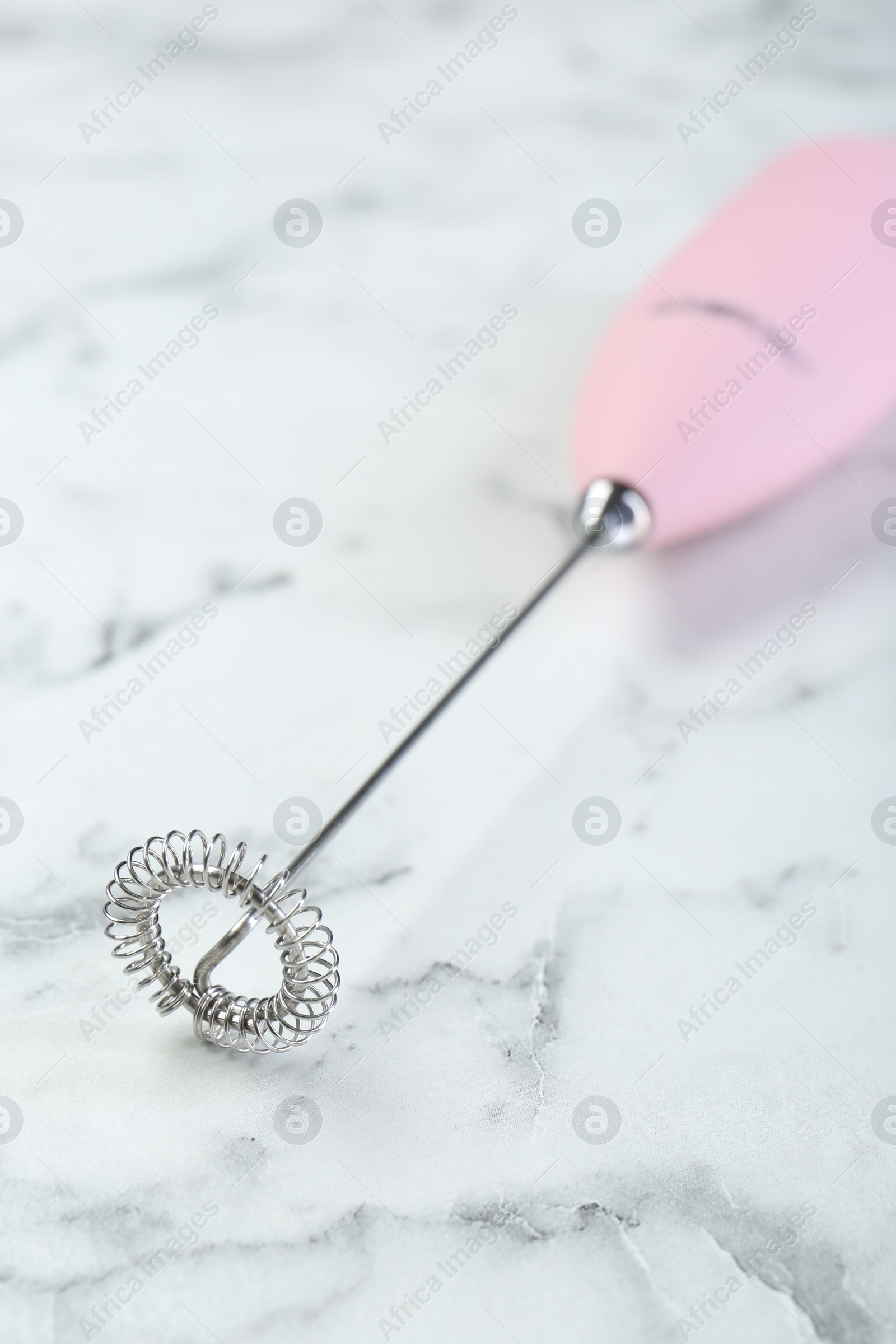 Photo of Pink milk frother wand on white marble table, closeup