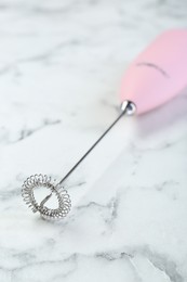 Photo of Pink milk frother wand on white marble table, closeup