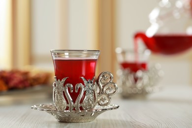 Photo of Glass of traditional Turkish tea in vintage holder on white wooden table. Space for text