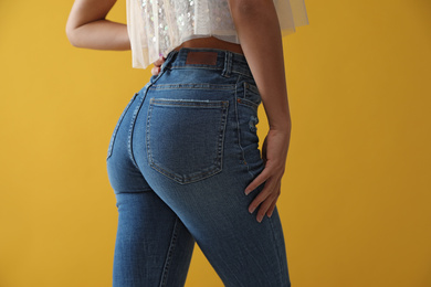 Photo of Woman wearing jeans on yellow background, closeup