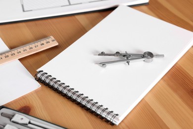 Sketchbook, pair of compasses and ruler on wooden table