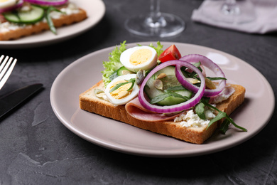 Photo of Tasty sandwich with ham and quail eggs served on grey table