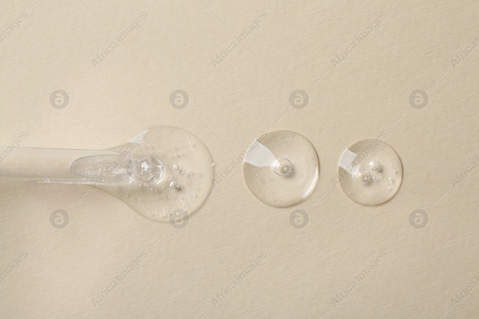 Photo of Pipette with cosmetic serum on beige background, macro view