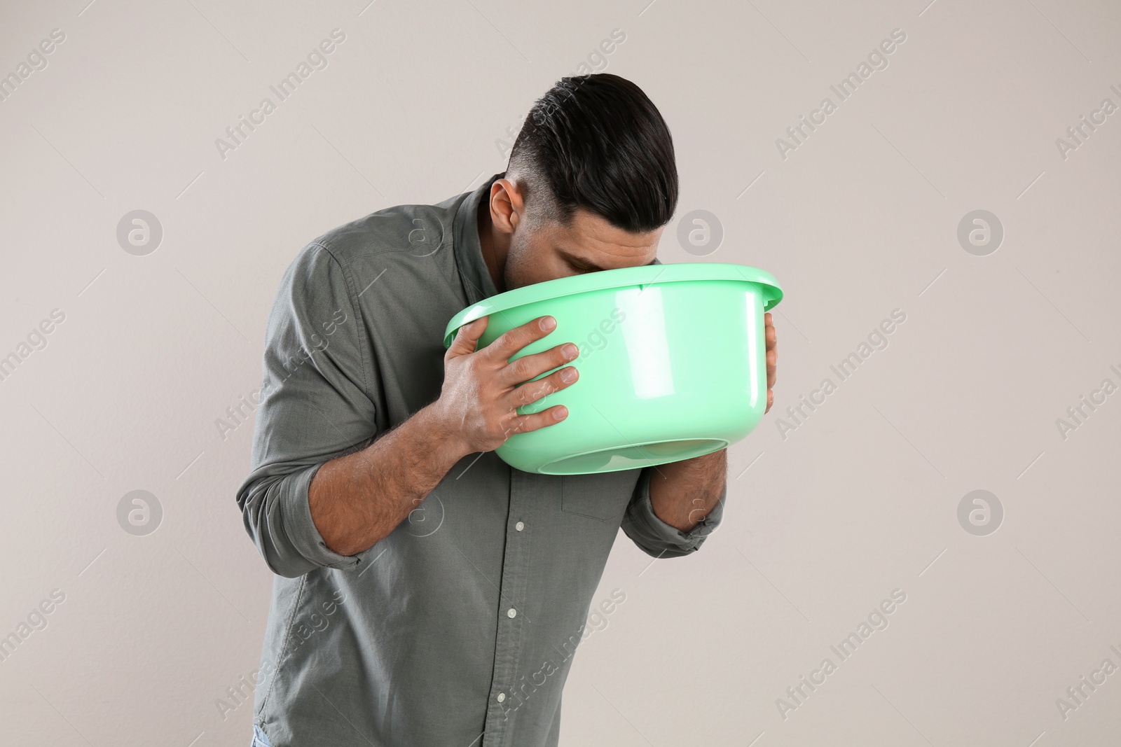 Photo of Man with basin suffering from nausea on beige background. Food poisoning