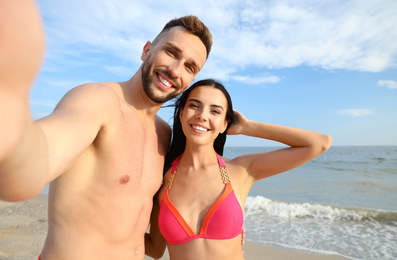 Photo of Happy young couple taking selfie on beach