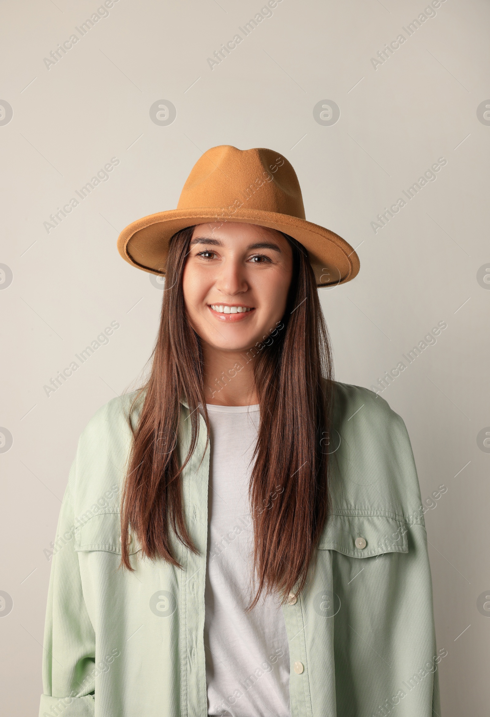 Photo of Smiling young woman in stylish outfit on light background