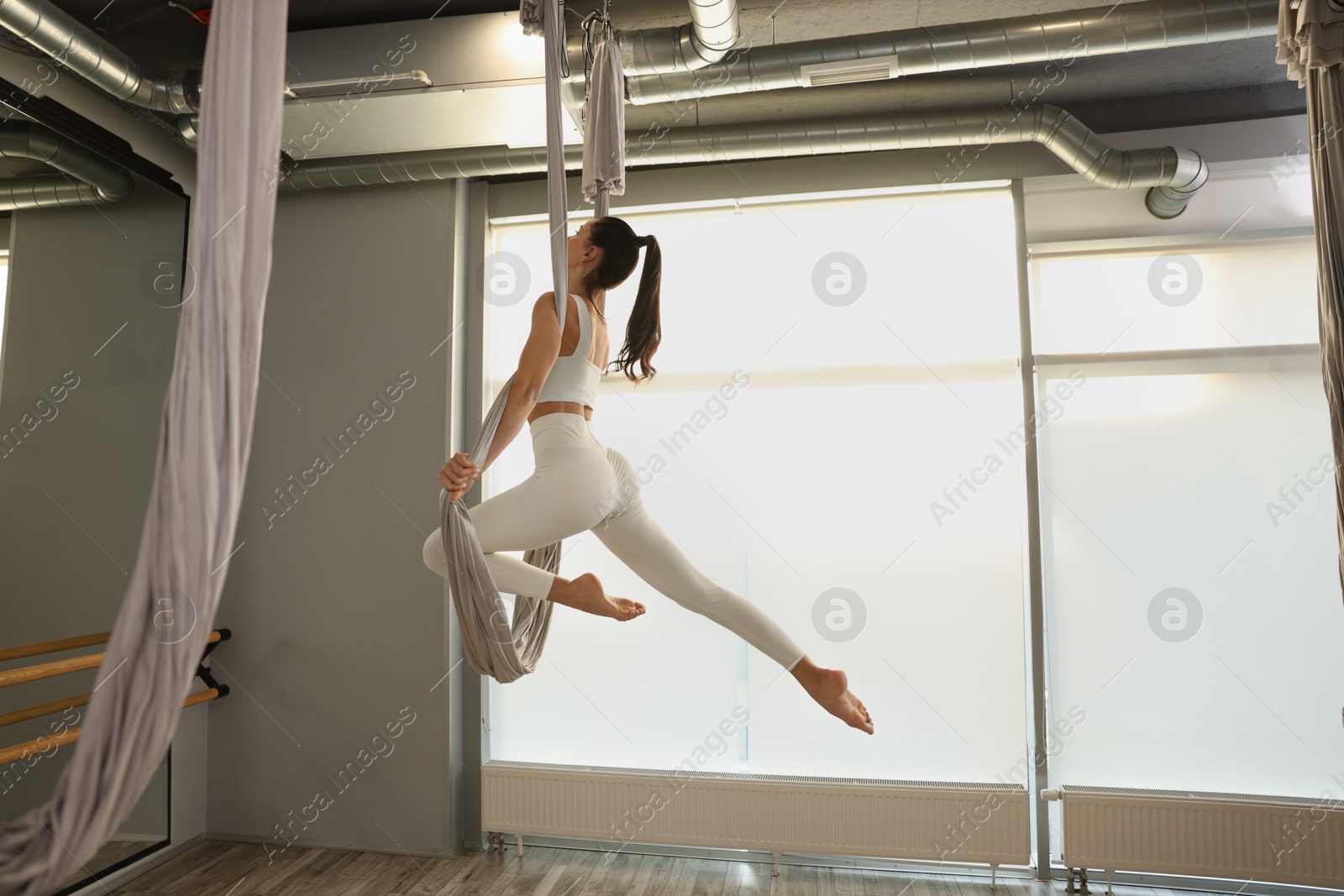 Photo of Young woman practicing fly yoga on hammock in studio