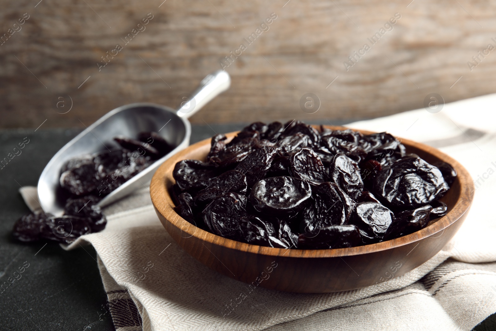 Photo of Plate and scoop of sweet dried plums on table. Healthy fruit