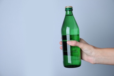 Photo of Woman holding glass bottle with water on white background, closeup. Space for text