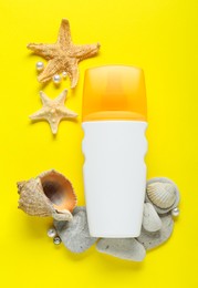 Bottle of suntan cream and seashells on yellow background, flat lay