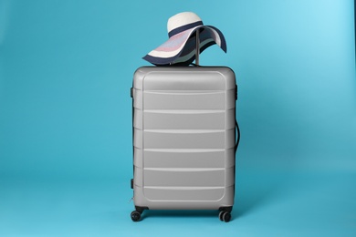Photo of Stylish suitcase with hat on color background