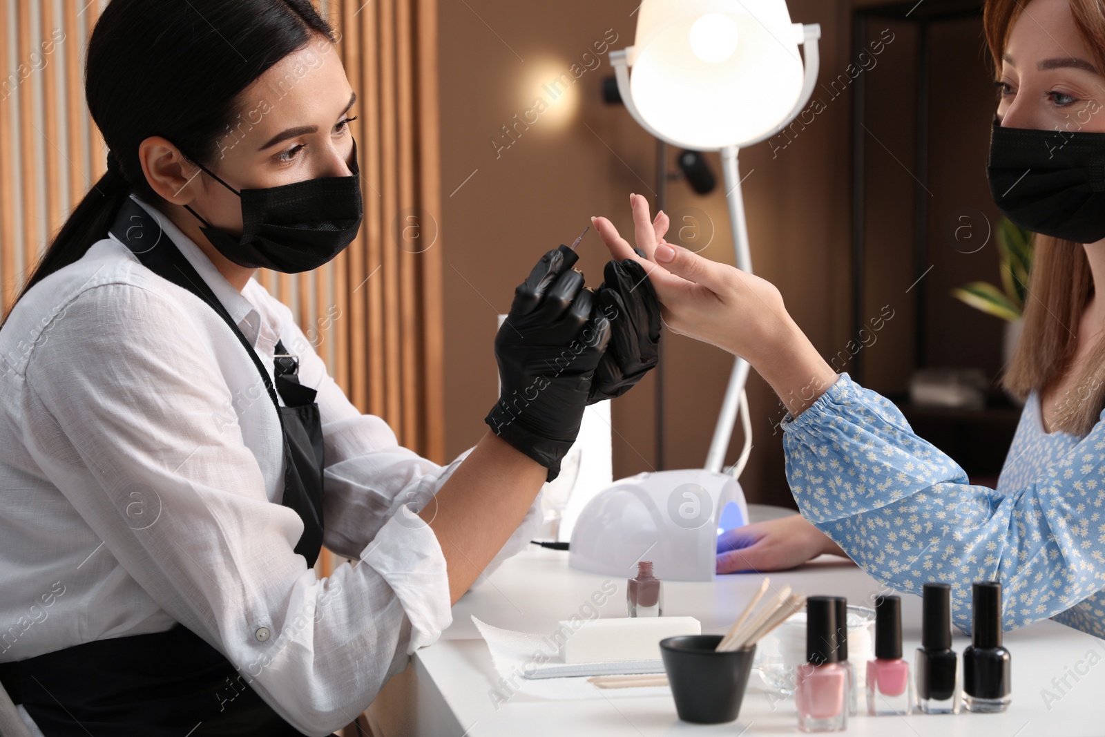 Photo of Professional manicurist working with client in salon. Beauty services during Coronavirus quarantine