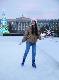 Happy young woman skating at outdoor ice rink