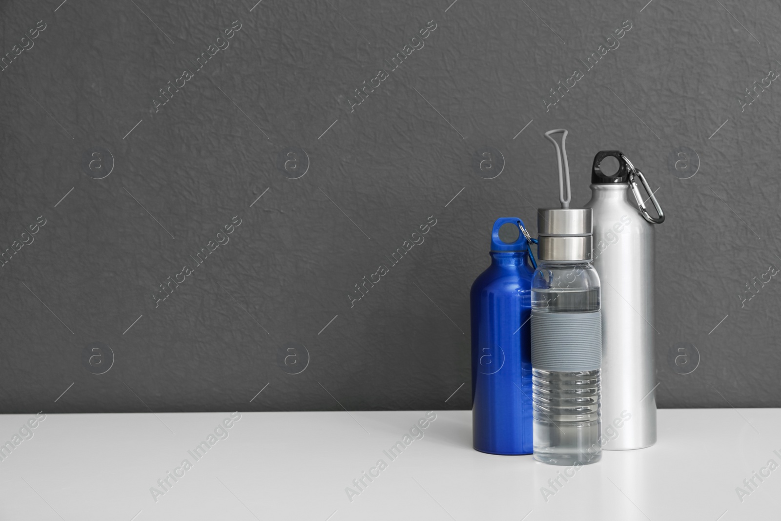 Photo of Different water bottles for sports on gray background. Space for text