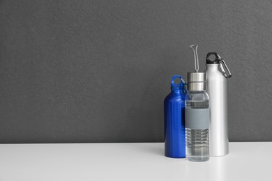 Photo of Different water bottles for sports on gray background. Space for text