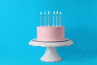 Photo of Birthday cake with burning candles on light blue background