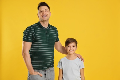 Portrait of dad and his son on color background