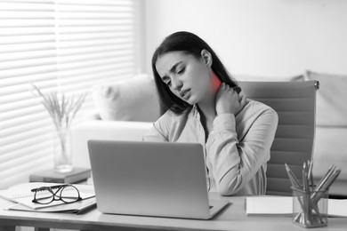 Woman suffering from neck pain at table, black and white effect