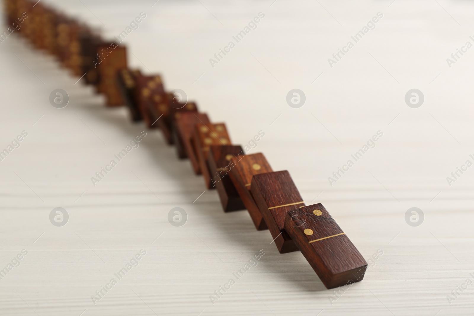 Photo of Wooden domino tiles falling on white table