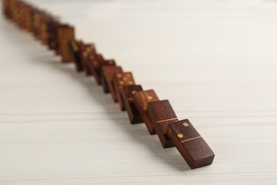 Wooden domino tiles falling on white table