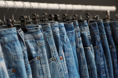 Photo of Rack with different jeans on dark grey background, closeup