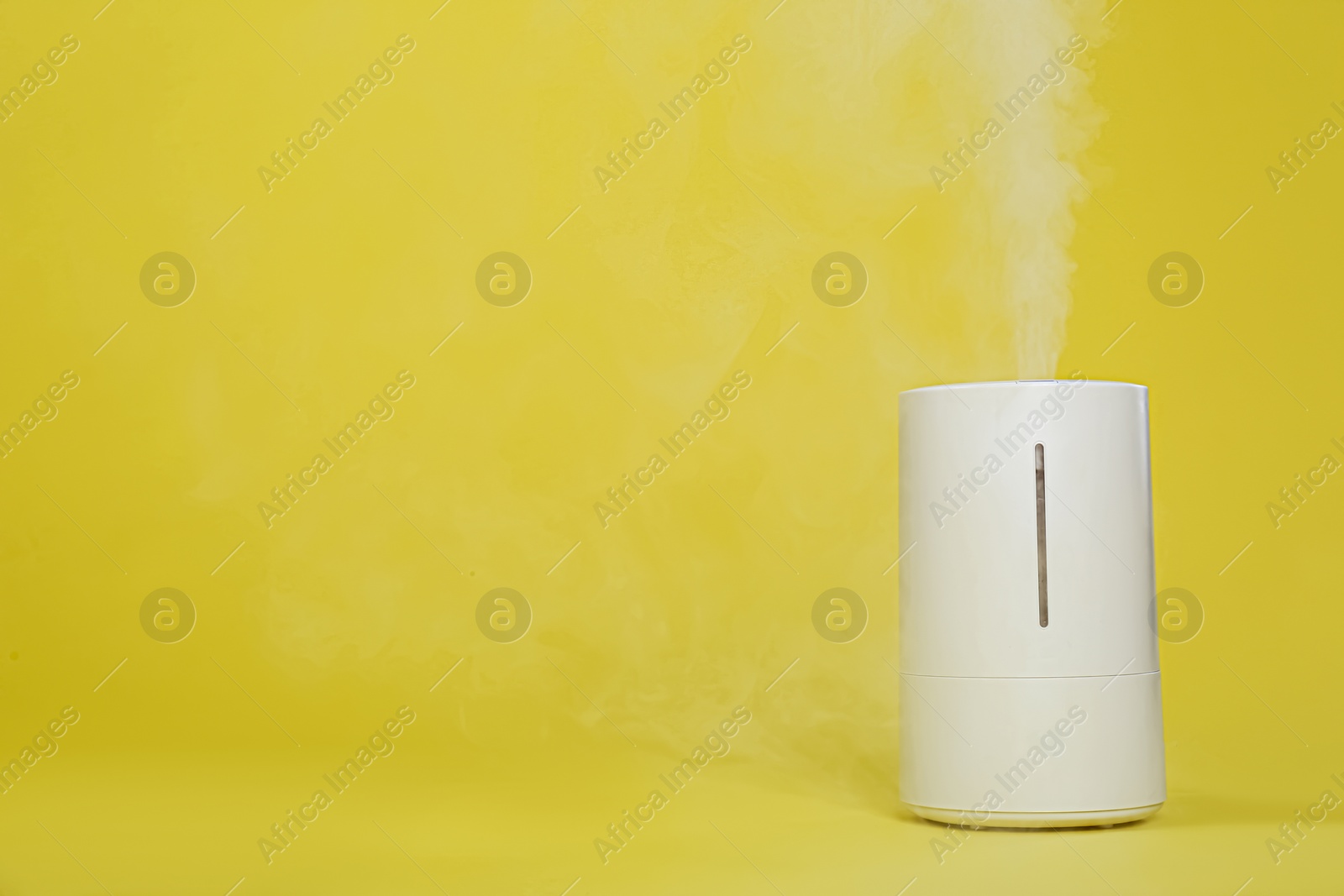 Photo of Modern air humidifier on yellow background. Space for text
