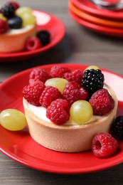 Photo of Delicious tartlet with berries on wooden table, closeup