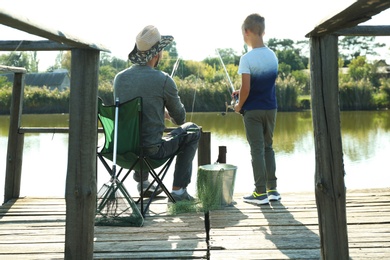 Photo of Father and son fishing together on sunny day