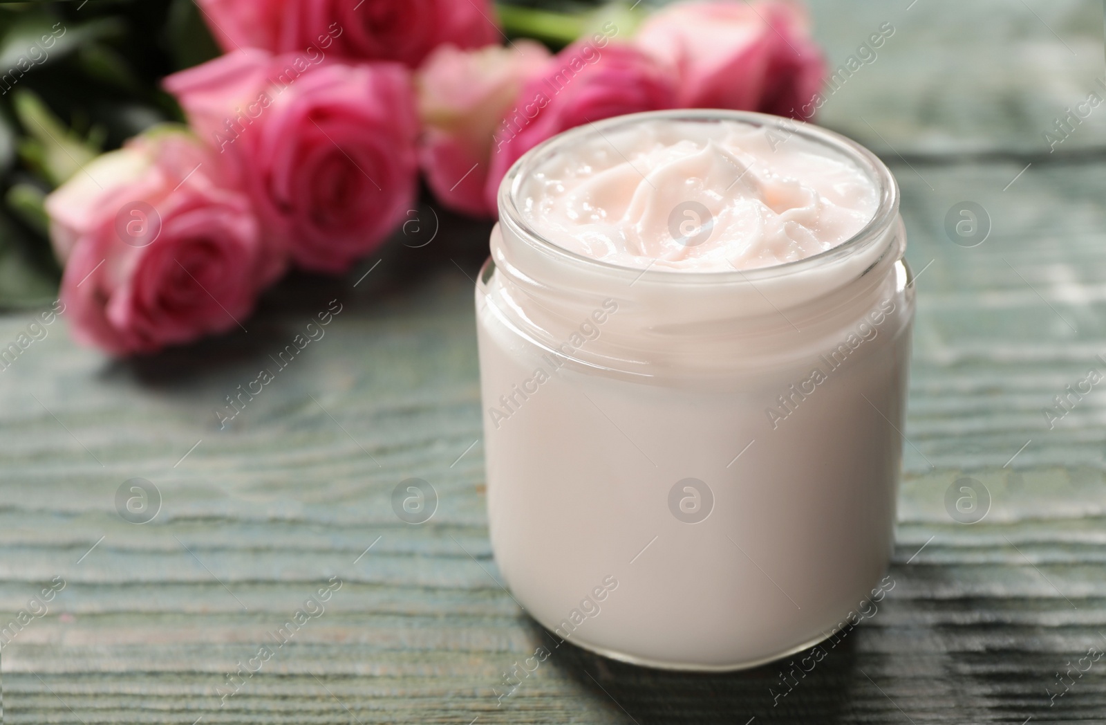 Photo of Jar of facial cream on light blue wooden table, space for text