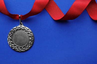 Gold medal with space for design on color background, top view. Victory concept