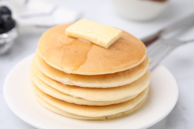 Photo of Delicious pancakes with butter and honey on white table, closeup