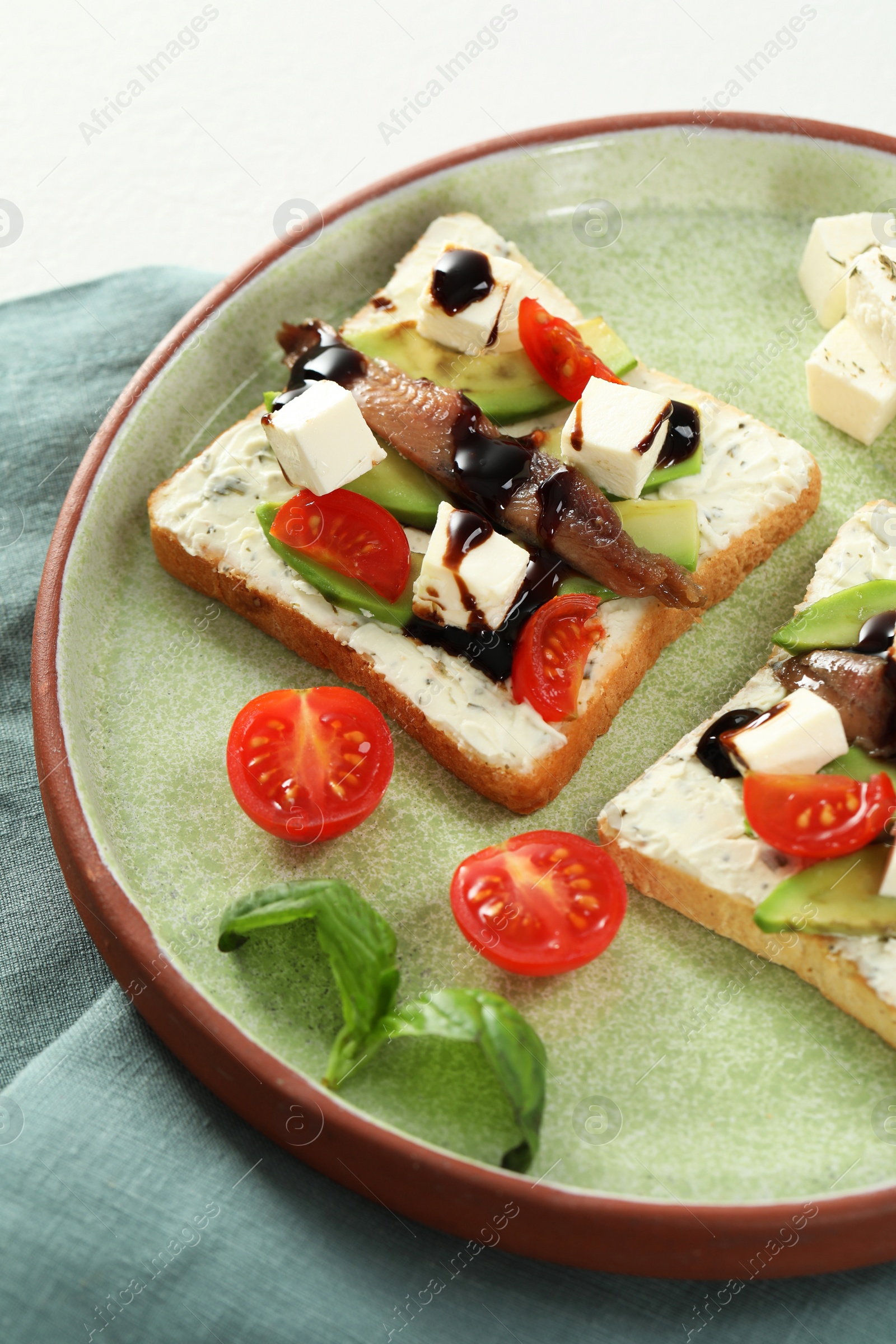 Photo of Delicious sandwiches with anchovies, cheese and tomato on white table