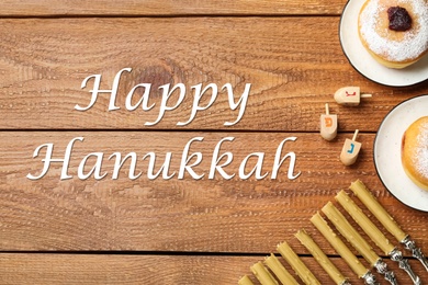 Happy Hanukkah. Flat lay composition with menorah, dreidels and sufganiyot on wooden table